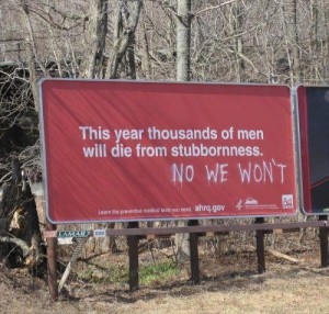billboard that says "this year thousands of men will die from stubbornness" and "no we won't" is spray painted under it